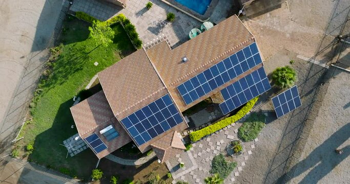 Aerial zoom out circular view of a reneweable energy efficient home with photovoltaic solar panels on a suburban house roof top