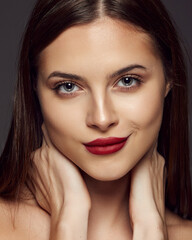 Portrait of young beautiful girl posing isolated over dark grey background. Nude makeup with bright red lips. Concept of beauty, fashion and cosmetology