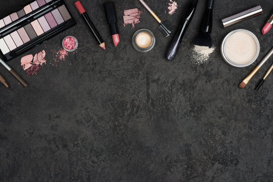 Makeup products with cosmetics palette and space on dark background