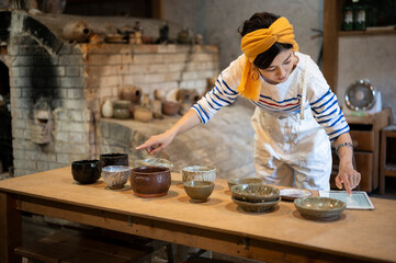 デジタルタブレットを使って商品管理をする陶芸家の女性