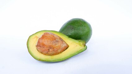 Green avocado fruit that has been split and is ripe. Contains many vitamins for human health. Placed on a white mat.
