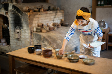 デジタルタブレットを使って商品管理をする陶芸家の女性