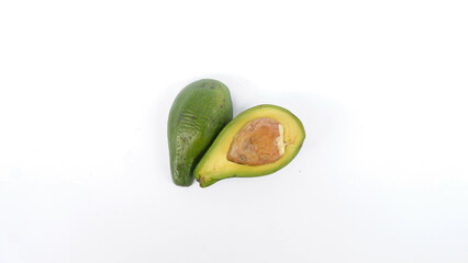 Green avocado fruit that has been split and is ripe. Contains many vitamins for human health. Placed on a white mat.
