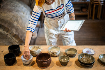 デジタルタブレットを使って商品管理をする陶芸家の女性