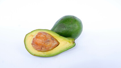 Green avocado fruit that has been split and is ripe. Contains many vitamins for human health. Placed on a white mat.
