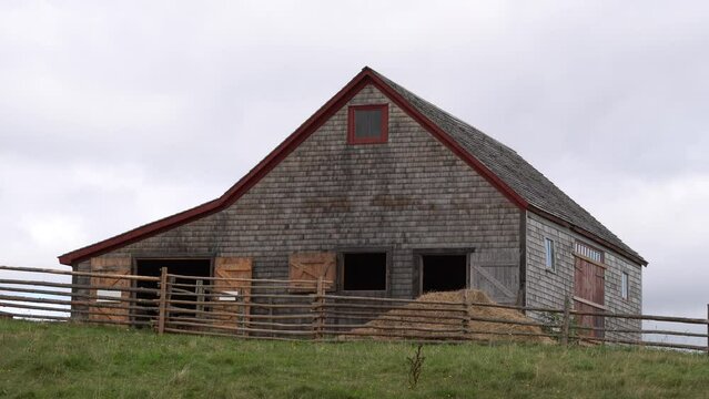 A beautiful barn made with wood on a farm. Behind you can see a cloudy sky.