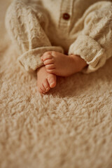 feet of a newborn, the baby is dressed in a warm knitted suit