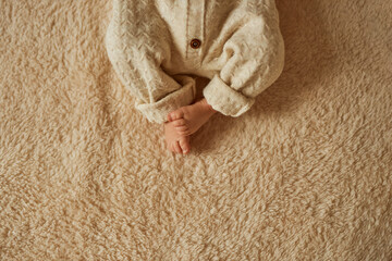 Fototapeta na wymiar feet of a newborn, the baby is dressed in a warm knitted suit