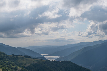 Fototapeta premium river flowing between the mountains in summer, cloudy blue sky 