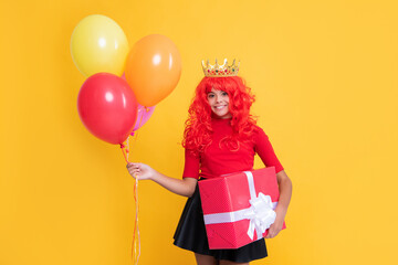 positive girl in crown with present box and party balloon on yellow background