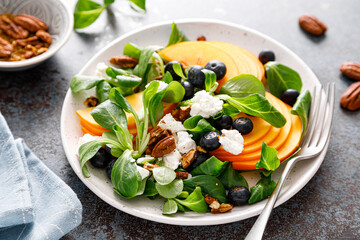 Persimmon fruit salad with blueberry, pecan nuts and ricotta chesse. Healthy food. Top view