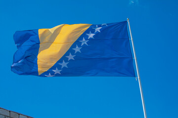 Flag of Bosnia and Herzegovina rise waving to the wind with sky in the background