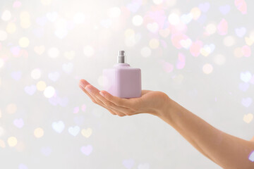 Female hand with perfume on light background