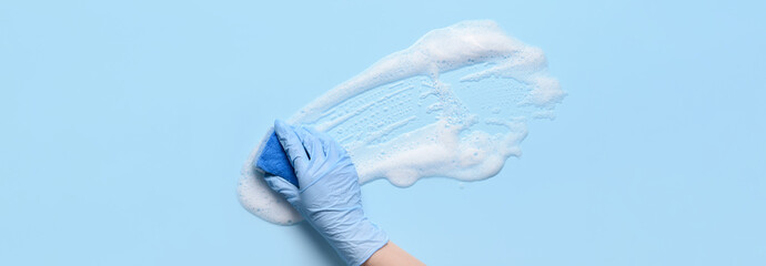 Fototapeta na wymiar Hand of woman with sponge cleaning light blue surface