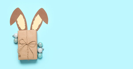 Paper bunny ears, Christmas gift and balls on light blue background with space for text