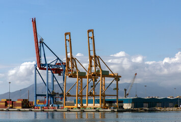 Fototapeta na wymiar Massive harbor cranes in seaport. Heavy load dockside cranes in port, cargo container yard, container ship terminal