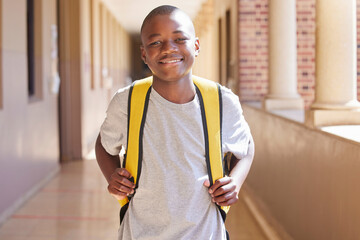 Student, child and backpack standing in school campus lobby for study. Back to school portrait, African boy and ready for education, learning or knowledge with happy smile in high school building