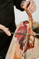 Profesional slicing Spanish jamon iberico (ham). Selective focus point