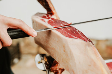 Profesional slicing Spanish jamon iberico (ham). Selective focus point