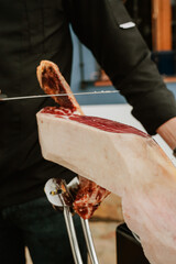 Profesional slicing Spanish jamon iberico (ham). Selective focus point