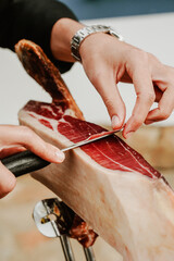 Profesional slicing Spanish jamon iberico (ham). Selective focus point