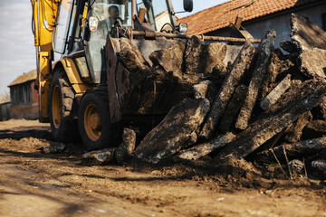 Fototapeta premium Selective focus on excavator collecting piles of asphalt on construction site.