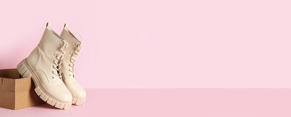 Cardboard box with stylish boots on pink background with space for text