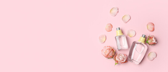 Bottles of perfume and rose flowers on pink background with space for text, top view