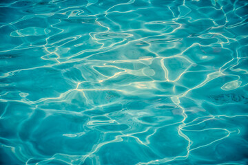 Azure clear water in a swimming pool with sun reflecting