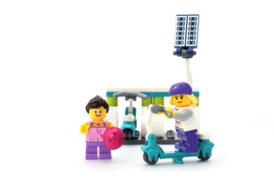 Lego minifigure of girl on electro scooter. Editorial illustrative image of usage of solar panel or photovoltaic as green energy and alternative power source.