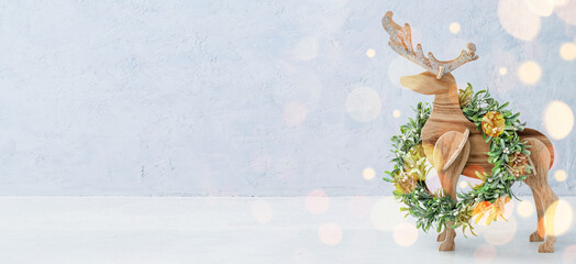 Wooden reindeer and Christmas wreath on light background with space for text