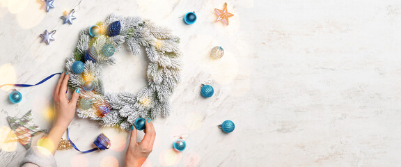 Hands of woman making beautiful Christmas wreath on light background with space for text
