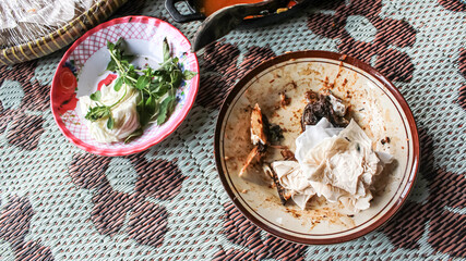 Empty dish plate with traces and pieces of food. Unfinished or finished lunch, dinner, breakfast bowl on table in kitchen. Dirty, empty, not clean. Spoon. Fork.
