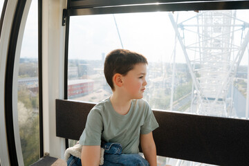 Child rides the Ferris wheel and is at the top. Vacation with kids. children's attractions