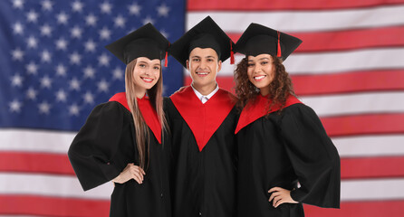 Young graduating students in bachelor robes against USA flag