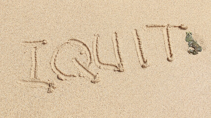 The word I QUIT is writting on the sand with wave. drawing on the sand. writing with sands on the beach. 