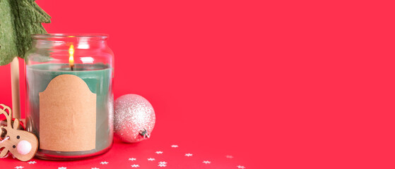 Jar with burning candle and Christmas decor on red background with space for text