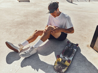 Skateboard, knee and injury with a sports man holding his leg joint in pain after a fall or...