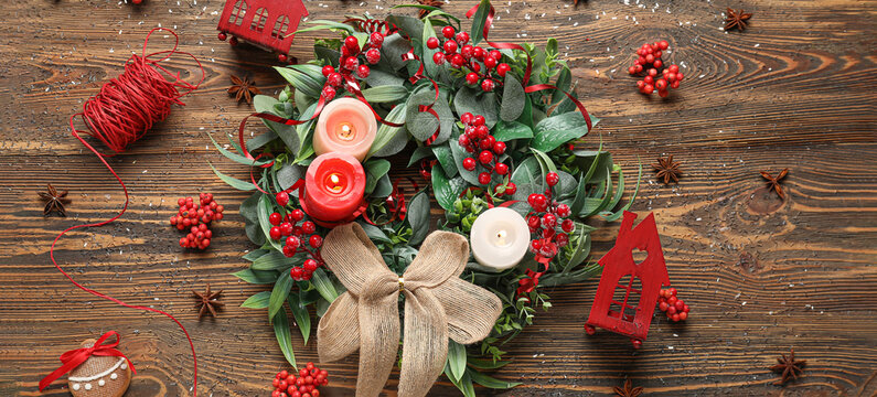 Stylish Christmas wreath with candles and decorations on wooden background, top view