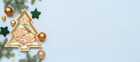 Plate in shape of Christmas tree with cookies, candies and decorations on light background with space for text