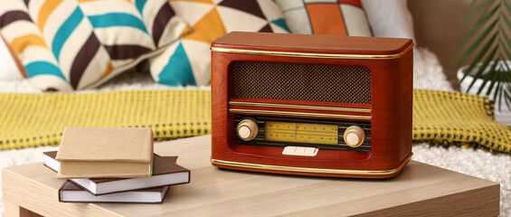 Retro radio receiver and books on table in room