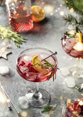 Pomegranate Christmas cocktail with rosemary and lemon on gray background with bokeh lights. Xmas drink