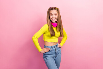 Portrait of funky toothy beaming girl with straight hairdo dressed yellow long sleeve arms on waist isolated on yellow color background