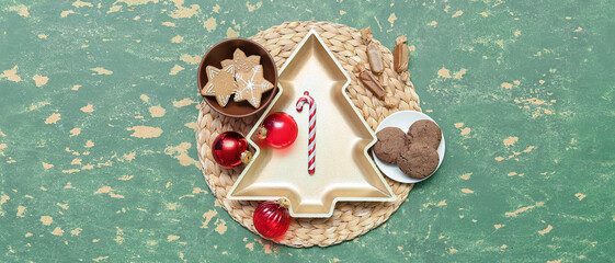 Plate in shape of Christmas tree with cookies, candies and balls on grunge background