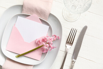 Table setting with blank card and hyacinth flower on white wooden background