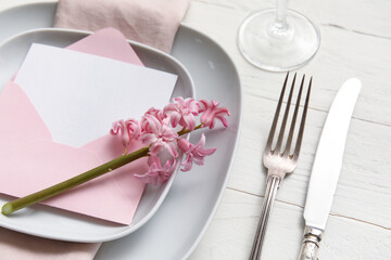 Table setting with blank card and hyacinth flower on white wooden background