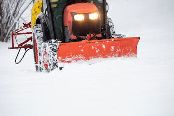Tractor cleaning urban park paths on a cold snowy day.