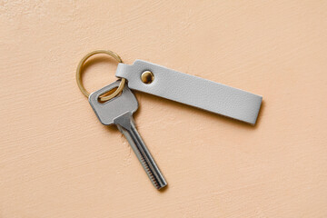 Metal key with leather keychain on beige background