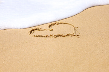 Drawn heart on sand near sea, closeup
