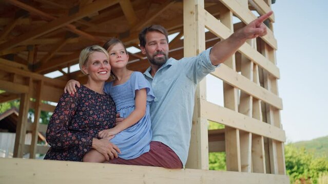 Happy family enjoying the view from their new future home on buidling site of sustainable house.